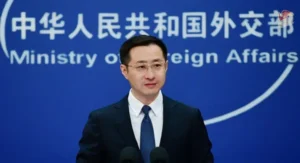 a man in a suit and tie standing in front of microphones